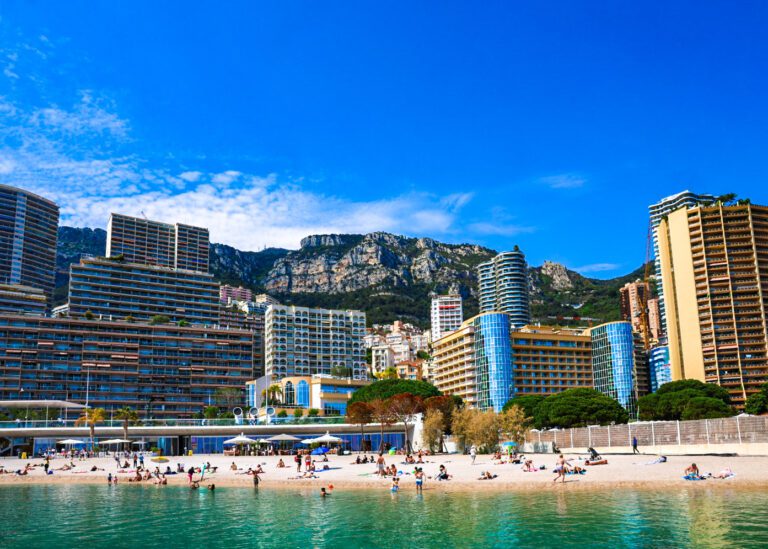 Scenic view of the beach in Monaco, France, with turquoise waters, golden sands, and coastal cliffs