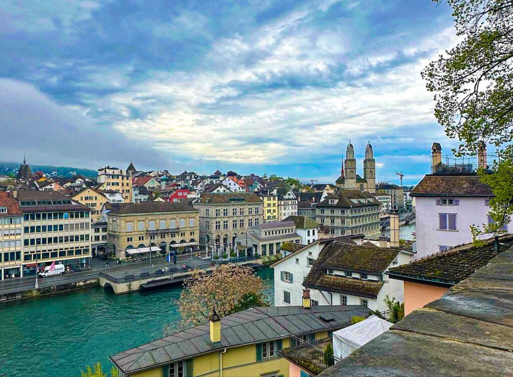 Captivated by the timeless charm of Zurich from Lindenhof Hill. A panorama of red rooftops, the Limmat River, and the distant Alps